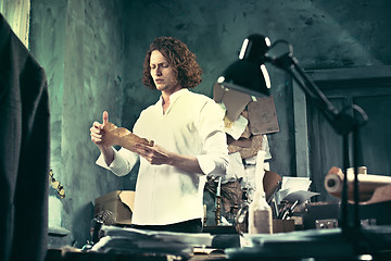 Image showing Writer at work. Handsome young writer standing near the table and making up something in his mind