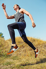 Image showing Running sport. Man runner sprinting outdoor in scenic nature. Fit muscular male athlete training trail running for marathon run.