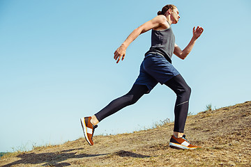 Image showing Running sport. Man runner sprinting outdoor in scenic nature. Fit muscular male athlete training trail running for marathon run.