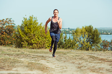 Image showing Running sport. Man runner sprinting outdoor in scenic nature. Fit muscular male athlete training trail running for marathon run.