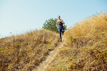 Image showing Running sport. Man runner sprinting outdoor in scenic nature. Fit muscular male athlete training trail running for marathon run.