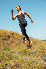 Image showing Running sport. Man runner sprinting outdoor in scenic nature. Fit muscular male athlete training trail running for marathon run.