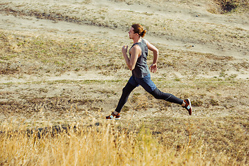 Image showing Running sport. Man runner sprinting outdoor in scenic nature. Fit muscular male athlete training trail running for marathon run.