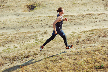 Image showing Running sport. Man runner sprinting outdoor in scenic nature. Fit muscular male athlete training trail running for marathon run.