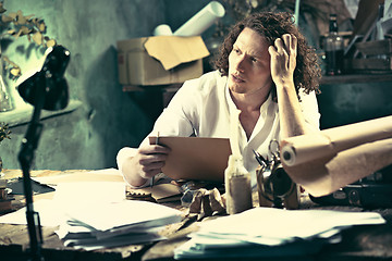 Image showing Writer at work. Handsome young writer sitting at the table and writing something in his sketchpad