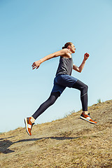 Image showing Running sport. Man runner sprinting outdoor in scenic nature. Fit muscular male athlete training trail running for marathon run.