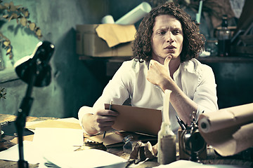 Image showing Writer at work. Handsome young writer sitting at the table and writing something in his sketchpad