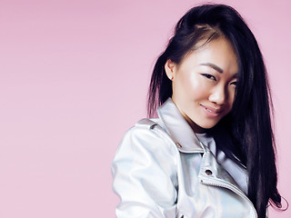 Image showing young pretty smiling asian korean girl wearing modern fashion clothers on pink background, lifestyle people concept 