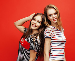 Image showing two best friends teenage girls together having fun, posing emotional on red background, besties happy smiling, lifestyle people concept close up