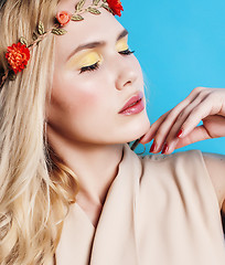 Image showing young pretty blond girl with curly blond hair and little flowers happy smiling on blue sky background, lifestyle people concept