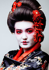 Image showing young pretty geisha in black kimono among sakura, asian ethno close up