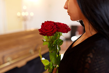 Image showing woman with red roses and coffin at funeral