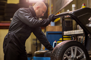 Image showing auto mechanic balancing car wheel at workshop