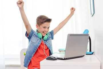 Image showing boy with headphones playing video game on laptop