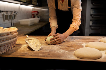 Image showing baker portioning dough with bench cutter at bakery