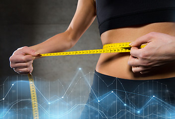 Image showing close up of woman measuring waist by tape in gym