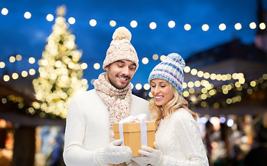 Image showing happy couple with gift box over christmas lights