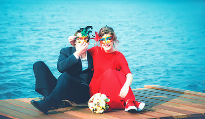 Image showing Happy Couple In Masquerade Masks Against A Turquoise Lake