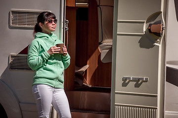 Image showing Woman is standing with a mug of coffee near the camper RV.
