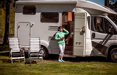 Image showing Woman is standing with a mug of coffee near the camper RV.