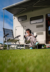 Image showing Woman is standing with a mug of coffee near the camper RV.