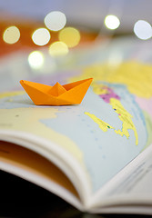 Image showing Paper boat on a atlas book 
