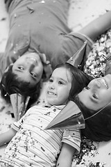 Image showing kids  blowing confetti while lying on the floor