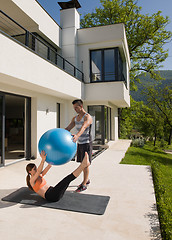 Image showing woman and personal trainer doing exercise with pilates ball