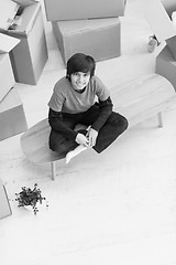 Image showing boy sitting on the table with cardboard boxes around him top vie