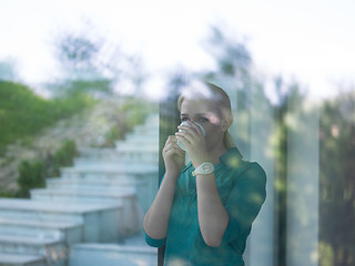 Image showing young woman drinking morning coffee by the window