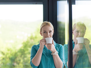 Image showing young woman drinking morning coffee by the window