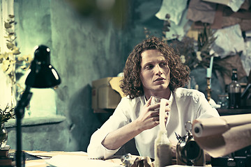 Image showing Writer at work. Handsome young writer sitting at the table and writing something in his sketchpad