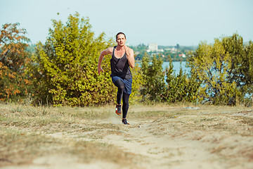 Image showing Running sport. Man runner sprinting outdoor in scenic nature. Fit muscular male athlete training trail running for marathon run.