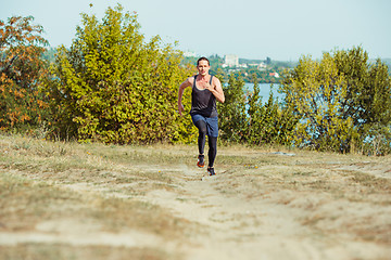 Image showing Running sport. Man runner sprinting outdoor in scenic nature. Fit muscular male athlete training trail running for marathon run.