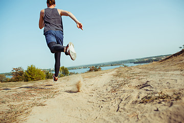 Image showing Running sport. Man runner sprinting outdoor in scenic nature. Fit muscular male athlete training trail running for marathon run.