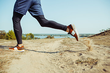 Image showing Running sport. Man runner sprinting outdoor in scenic nature. Fit muscular male athlete training trail running for marathon run.