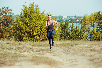 Image showing Running sport. Man runner sprinting outdoor in scenic nature. Fit muscular male athlete training trail running for marathon run.