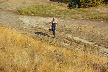 Image showing Running sport. Man runner sprinting outdoor in scenic nature. Fit muscular male athlete training trail running for marathon run.