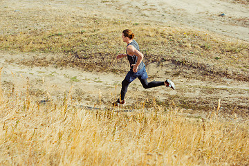 Image showing Running sport. Man runner sprinting outdoor in scenic nature. Fit muscular male athlete training trail running for marathon run.