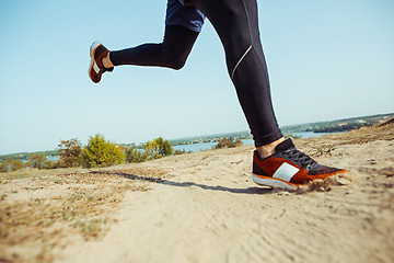 Image showing Running sport. Man runner sprinting outdoor in scenic nature. Fit muscular male athlete training trail running for marathon run.