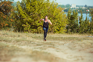 Image showing Running sport. Man runner sprinting outdoor in scenic nature. Fit muscular male athlete training trail running for marathon run.