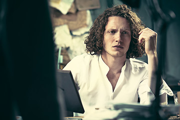 Image showing Writer at work. Handsome young writer sitting at the table and writing something in his sketchpad