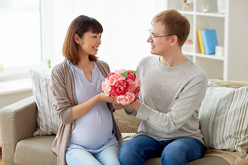 Image showing happy husband giving flowers to his pregnant wife