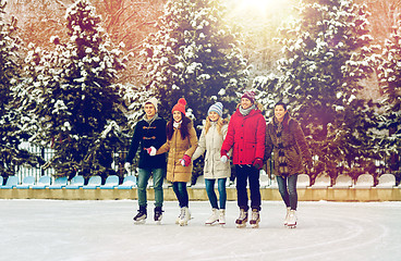 Image showing happy friends ice skating on rink outdoors