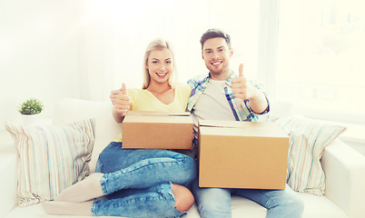 Image showing happy couple with boxes showing thumbs up at home