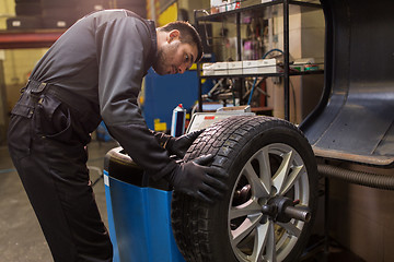 Image showing auto mechanic balancing car tire at workshop