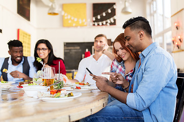 Image showing happy friends with smartphones at restaurant