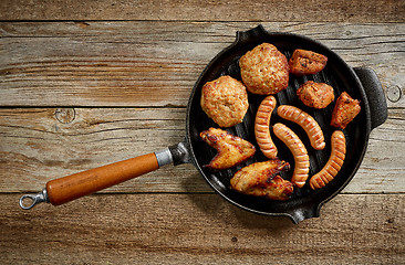 Image showing various grilled meat and fried potatoes on cast iron pan