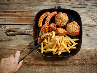 Image showing various grilled meat and fried potatoes on cast iron pan