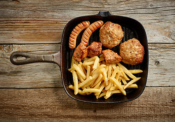 Image showing various grilled meat and fried potatoes on cast iron pan